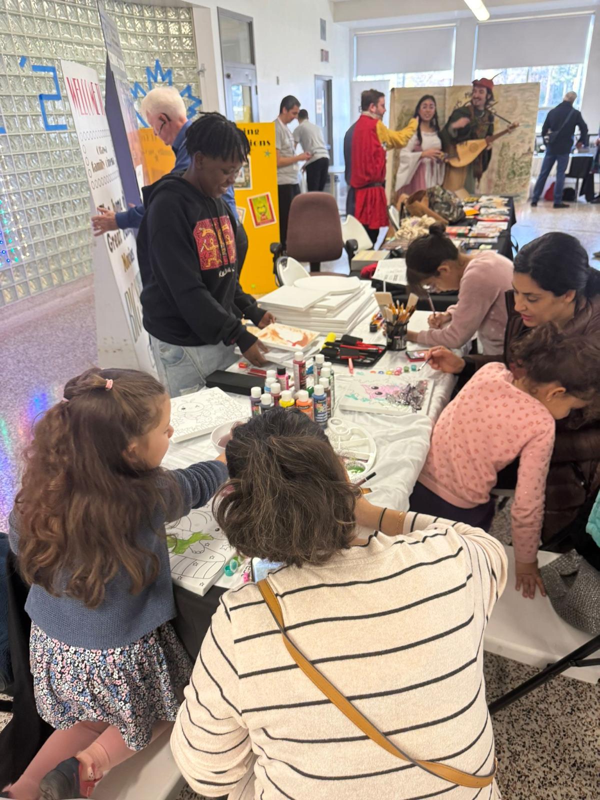 Families and youth gathered around a community arts table