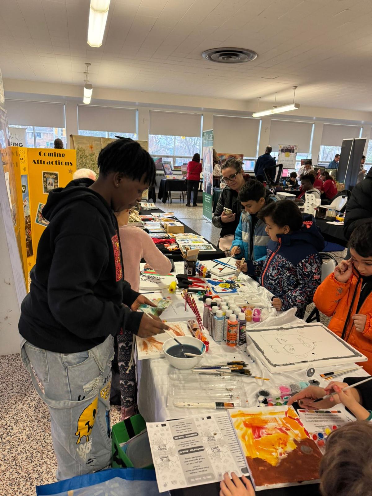 Youth and families painting together at a busy event table
